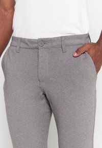 Gray textured trousers with a button closure, side pockets, and a straight fit. The fabric has a subtle pattern and smooth finish.