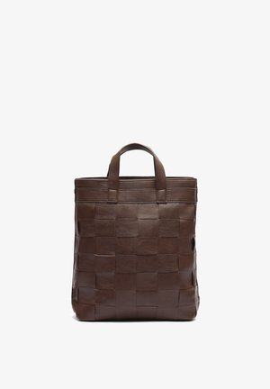 Sac cabas en cuir marron avec un motif carré tissé et deux courtes poignées, debout sur un fond blanc.