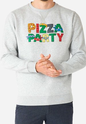 Sweat-shirt gris avec le texte coloré "PIZZA PARTY" comprenant des pizzas et des visages de tortues dessinés sur les lettres, porté par une personne aux mains jointes.