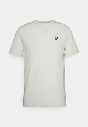 Wit T-shirt met korte mouwen en ronde hals met klein geel vogel-logo op de linkerborst, afgebeeld tegen een lichte achtergrond.