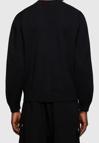 Cardigan nero lavorato a maglia con maniche lunghe e colletto a coste. Presenta una superficie texturizzata e una vita aderente all'orlo.