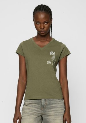 T-shirt vert olive en V fabriqué en coton doux. Présente un imprimé graphique blanc d'une main tenant une rose et le texte "SEULEMENT L'AMOUR". Manches courtes.