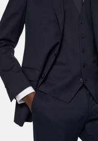 Marinblå skräddarsydd kostym med slagkrage, enkelknäppt design och väst. Tyget är slätt med fin textur; inkluderar sidofickor.