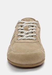 Beige suede sneaker with textured surface, featuring flat, speckled grey laces and a round toe. Stitched detailing on the vamp and sides.