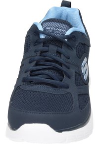 Zapatilla deportiva azul marino con parte superior de malla y sintético, collar acolchado, cierre con cordones y suela blanca. Presenta el logo en el lateral.