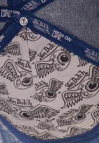 Notranjost klobuka Von Dutch vključuje modri fabrikovan rob, s podloženjem, ki prikazuje črne krilate oči in logotipe na svetli podlagi.