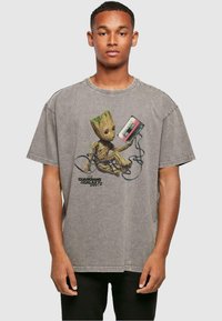 Grijze oversized t-shirt met een afbeelding van een cartoonfiguur die een cassettebandje vasthoudt, met daaronder de tekst "Guardians of the Galaxy Vol. 2".
