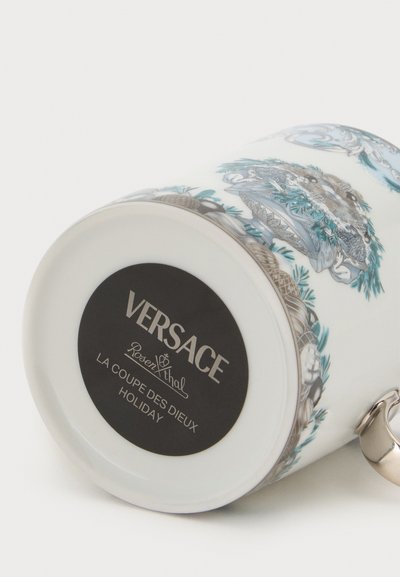 Λευκή κεραμική κούπα Versace με θέμα τις διακοπές, χρυσή λαβή, λεπτομερή μπλε και γκρι διακοσμητικό μοτίβο και λογότυπο της μάρκας στο κάτω μέρος.