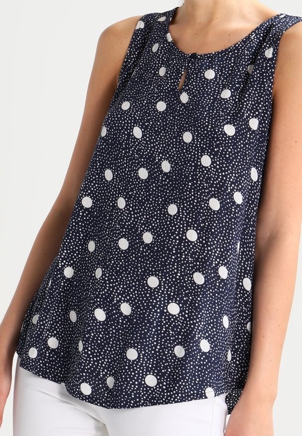 Marinblus utan ärmar med rund halsringning, med en öppen detalj och vita prickar i olika storlekar på ett strukturerat tyg.