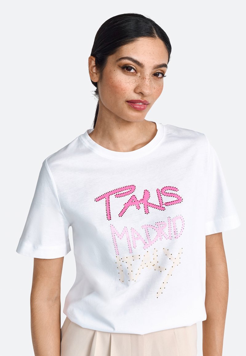 Tricou din bumbac alb, cu un text colorat din strasuri care spune "PARIS MADRID" în roz și auriu. Mâneci scurte și guler rotund.