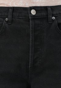 Black denim jeans featuring a high waist, classic five-pocket design, and silver button hardware with a slight texture.