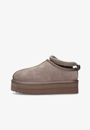 Beige suède instappers met een gebreide kraag. Voorzien van een dikke, bruine plateauzool met gegroefde randen en gestikte details.
