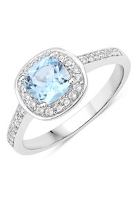 Bague en argent avec une pierre taille coussin de couleur bleu clair, entourée de petites pierres claires. Bande lisse avec des accents scintillants sur les côtés.