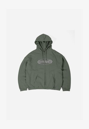 Olivno zelena zip-up kapuca s kenguru žepom, rebrastim manžetama i kontrastnim sivim grafičkim tekstom na prsima. Mekani pamučni materijal.