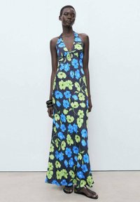 Halter-neck maxi dress in dark fabric with bright blue and green floral patterns; features a fitted bodice and flowing skirt.