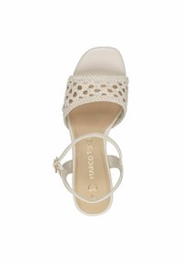 Sandale en cream légère et tissée avec une larges lanière et une boucle à la cheville. Présente une semelle intérieure beige lisse et un design minimaliste.