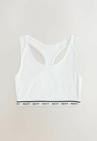 Sutien sport alb din material neted, cu un design racerback și o bandă neagră cu textul "NEXT" de-a lungul marginii inferioare.