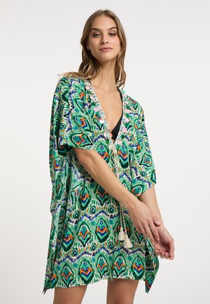 Zielona kaftan w wzory z krótkimi rękawami, ozdobiony skomplikowanymi wzorami w odcieniach pomarańczowego i niebieskiego. Posiada dekolt w kształcie litery V oraz dekoracyjne frędzle.