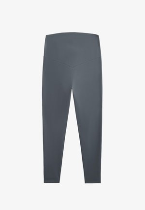 Szare legginsy z gładkiego, elastycznego materiału. Wysoki stan z detalem w kształcie litery V z tyłu, dopasowane nogawki, bez widocznych wzorów ani akcentów.