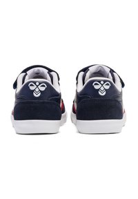 Blauwe leren sneakers met witte rubberen zolen. Beschikt over een ontwerp met rode accenten en een logo op de hiel. Klittenbandsluiting op de bovenkant.
