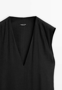 Mustat hihattomat mekko, jossa on syvä V-pääntie, sileä pinta ja minimalistinen muotoilu. Vuodessa lukee "Massimo Dutti" kaula-aukossa.