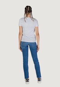 T-shirt bianco a maniche corte abbinato a jeans blu aderenti. Il tessuto sembra liscio e i jeans presentano un classico design a cinque tasche.
