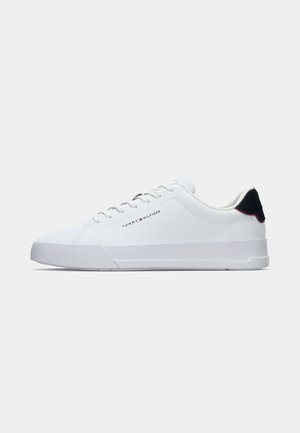 White low-top sneaker with white laces, navy heel tab, and "Tommy Hilfiger" logo on the side.