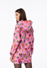 Kapuzenkleid in Pink mit lebhaften Herz- und Flammenmotiven. Hat lange Ärmel und eine lockere Passform, gefertigt aus weichem, leichtem Stoff.