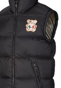 Schwarze Daunenweste ohne Ärmel, mit gestepptem Design und einem Teddy-Bären-Patch in Braun-, Weiß- und Grüntönen auf der Brust.