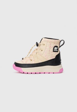 Botte d'hiver montante pour enfants en beige avec des motifs roses, bord noir, semelle rose et logo SOREL sur le côté et la boucle au talon.
