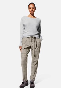 Grijze geribde trui, beige geruite broek met een strikceintuur en grijze schoenen met versieringen. Eenvoudige, moderne pasvorm en ontwerp.