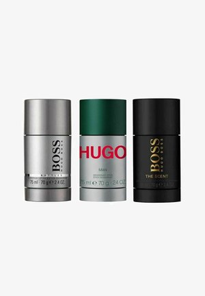 Tre deodorantstænger: sølv til "BOSS Bottled," grøn med rød tekst til "HUGO Man," og sort til "BOSS The Scent," alle cylindriske, 75 ml.
