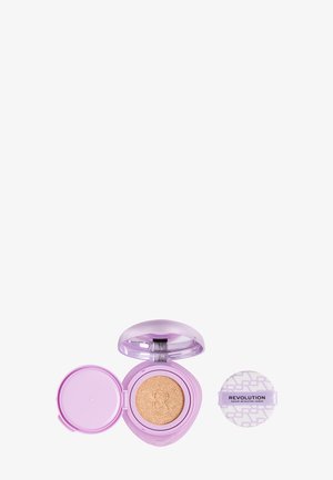 Estuche compacto en color lavanda con base de maquillaje beige en formato cushion y aplicador redondo separado con la etiqueta "Revolution Makeup Revolution London."