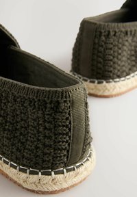 Grønne vævede espadrilles med en tekstureret overdel og en jutesål, der har hvid syning langs bunden og en struktureret stofkrave.