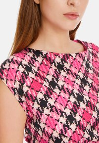 Ärmelloses Kleid mit einem lebhaften pinken und schwarzen abstrakten Muster, aus einem glatten Stoff gefertigt, mit rundem Ausschnitt und lockerer Passform.