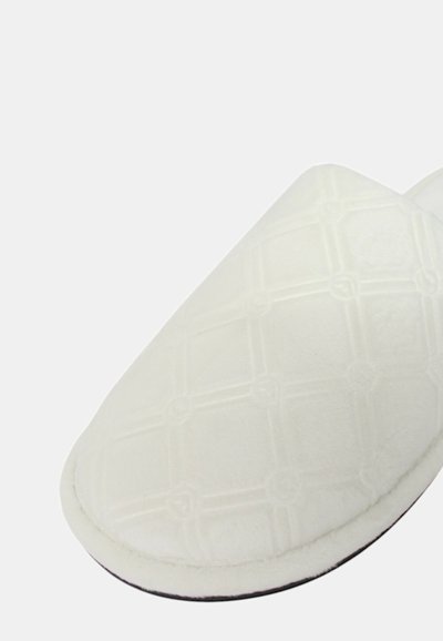 Pantofole bianche con una morbida texture in stoffa, caratterizzate da un motivo trapuntato, design con punta tonda e suola scura.