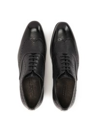 Chaussures habillées en cuir noir avec des détails en brogue, présentant un dessus texturé, un bout arrondi et des lacets pour un maintien sécurisé.