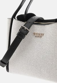 Silver perforated handbag with a black leather strap, zip closure, and metallic brand logo detail on the front.