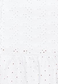 Bílá bavlněná šaty s jemnou vyšívanou krajkou, se textura povrchu a volánkovým lemem, který vytváří vrstvený efekt.