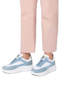 Helle blaue und weiße Sneaker mit Wildleder- und Lederelementen, ausgestattet mit einer dicken weißen Sohle und blauen Schnürsenkeln, kombiniert mit pinken cropped Hosen.