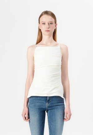Witte, getailleerde cami-top met gerimpelde structuur, dunne spaghetti-schouderbandjes en een vierkante halslijn, gecombineerd met blauwe, strakke jeans.