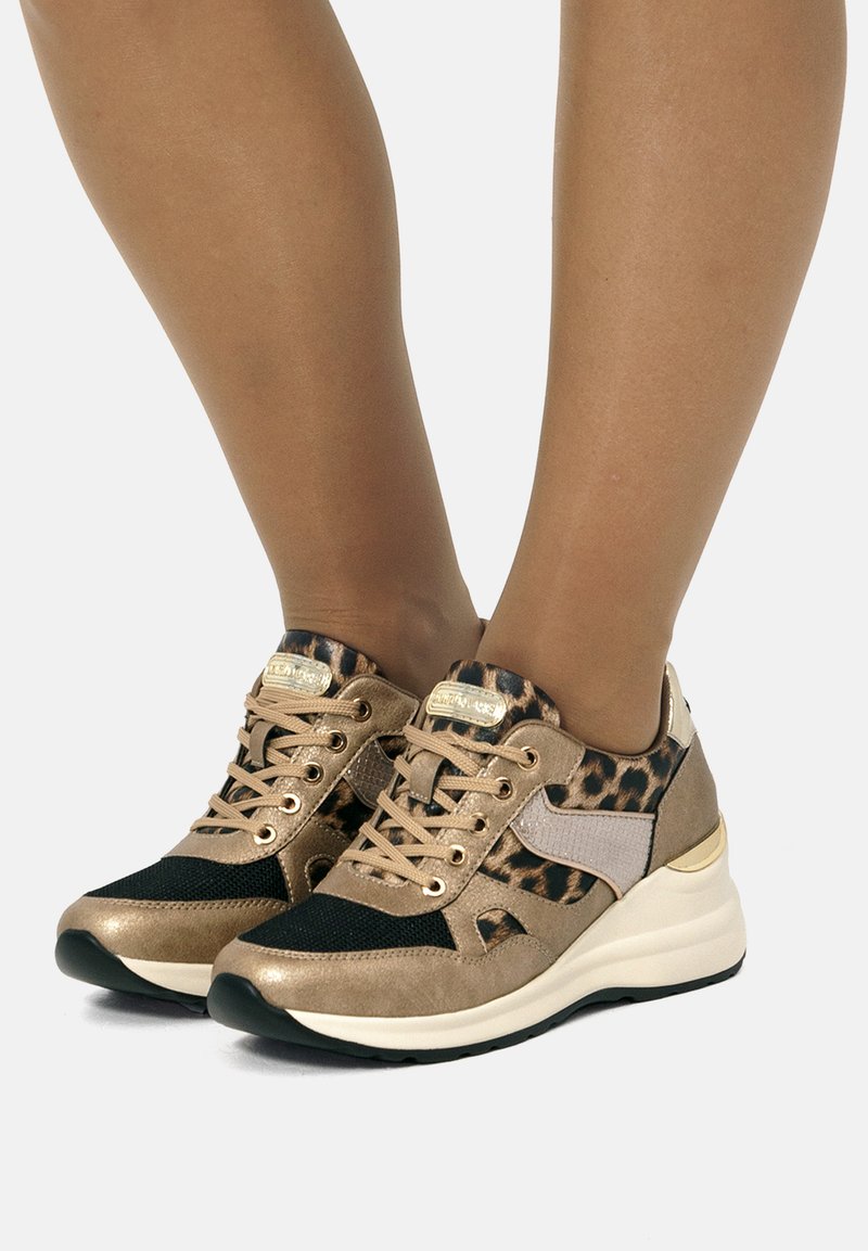 Zapatillas deportivas en color dorado y negro con acentos de estampado de leopardo, material de ante y malla, puntera redondeada y diseño de suela acolchada.