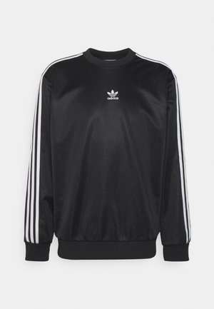 Czarna bluza Adidas z białymi trzema paskami na rękawach i małym logo Adidas umieszczonym na środku klatki piersiowej.