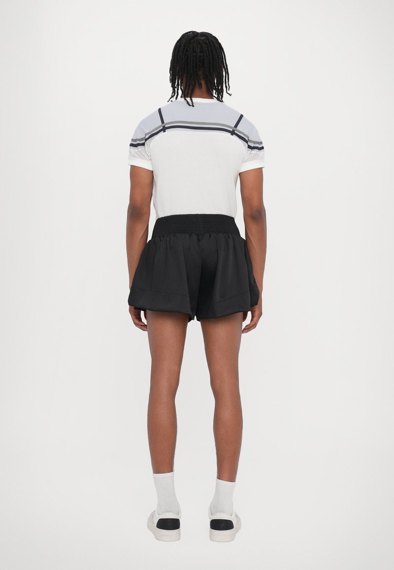 Sorte, lagdelte shorts med en tekstureret talje, parret med en lys grå T-shirt med korte ærmer, der har mørke striber og mesh-detaljer.