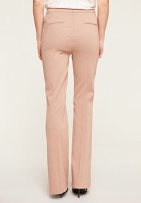 Pantaloni su misura con finitura metallica rosa, dal taglio dritto. Presentano due tasche posteriori e si posizionano in vita. Tessuto liscio.