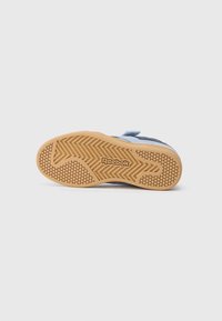Blue and navy sneaker with a gum rubber outsole featuring a herringbone pattern and hexagonal grip design; velcro closure visible.