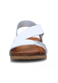 Sandali bianchi con un design a fascia incrociata, upper in morbida pelle e suola testurizzata marrone. L'interno presenta una soletta liscia di colore marrone chiaro.