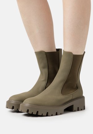 Khaki ankelstøvler med elastiske sidepaneler, runde tæer og en kraftig, tekstureret gummisål. Glat overflade med en ensfarvet farve.