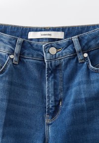 Lichtblauwe spijkerbroek met een gladde textuur, met een zilveren knoopsluiting, contrasterende stiksels en een label met de tekst "someday."