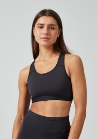 Zwarte sportbh met een ronde halslijn, brede bandjes en een ondersteunende band. Gemaakt van een gladde, rekbare stof, ontworpen voor comfort en beweging.
